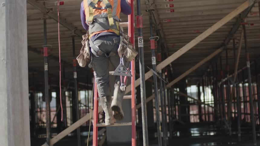A construction worker is climbing down a ladder