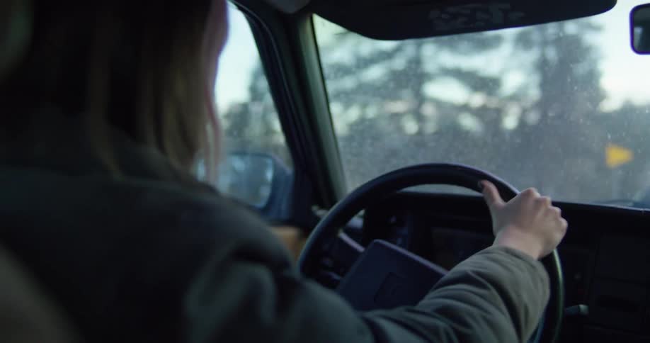 A woman drives a vehicle along a road during the day
