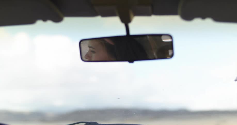 A woman looks in her rearview mirror as she drives a vehicle