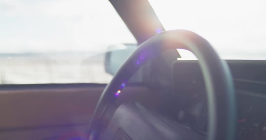 A woman driving a vehicle and turning the steering wheel with the sky and clouds in the background