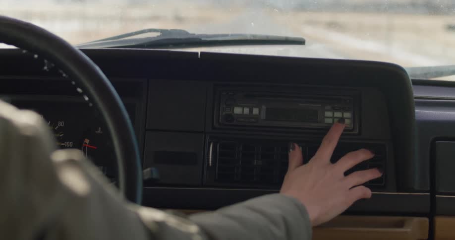 A woman driving a car and adjusting the vents