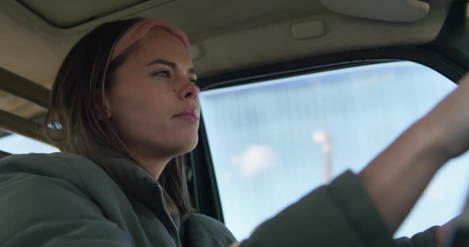 Woman with pink highlights on her hair driving a car