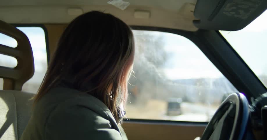 Woman with pink highlights on her hair driving a car
