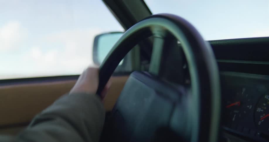 Woman wearing a hoodie driving a car on a rural road at daytime