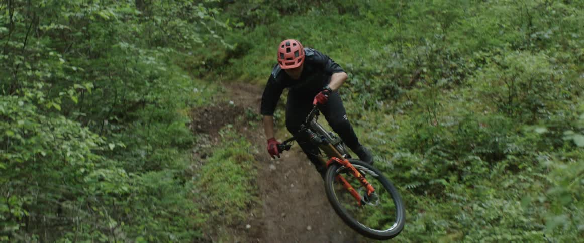 A man on mountain bike travelling at high speed hits jump and performs table trick