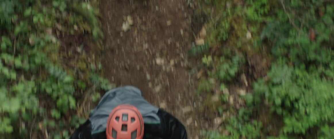 A man in a helmet rides downhill on a mountain bike at a very high speed