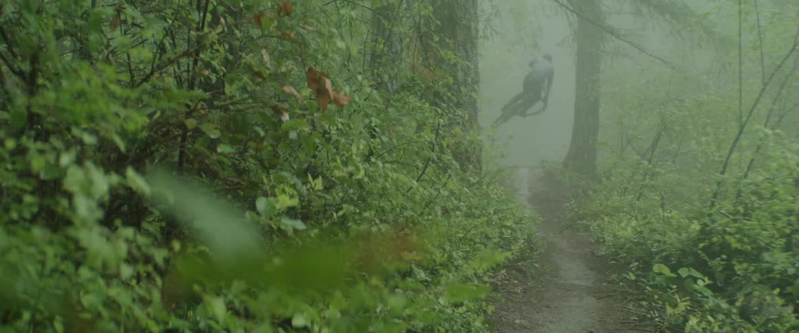 A person riding a mountain bike through deep puddles on forest trail and then hitting jump