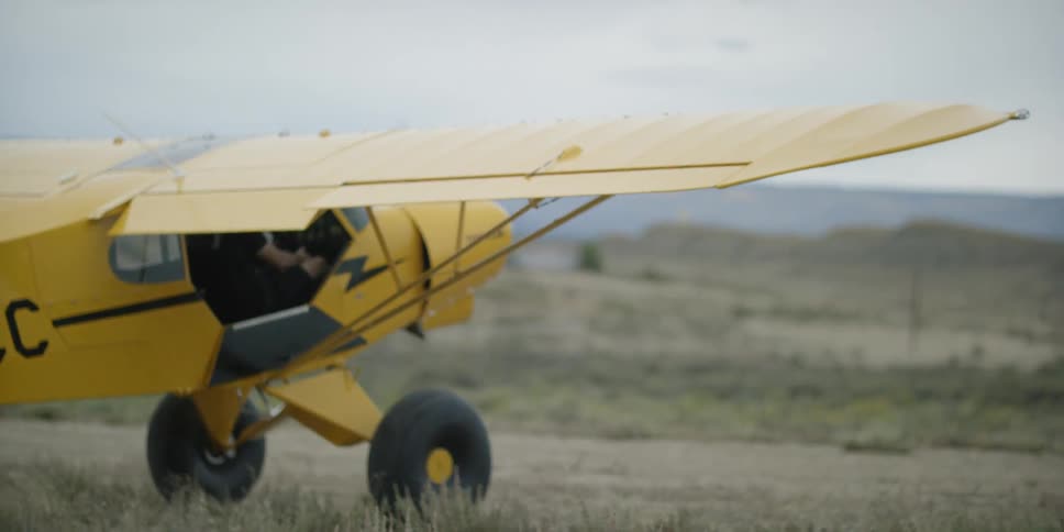 Small yellow plane coming to a stop on a dirt runway