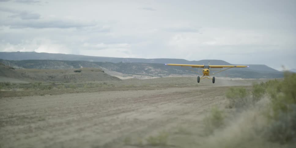 A small airplane takes off from dirt runway