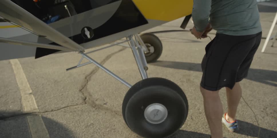 A man walks over to a wheel of a plane