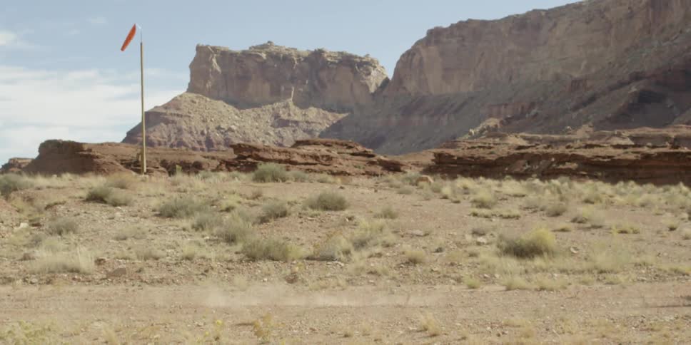 A small airplane travels by a desert background quickly