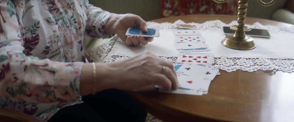 Woman playing solitaire on a table in the living room at home