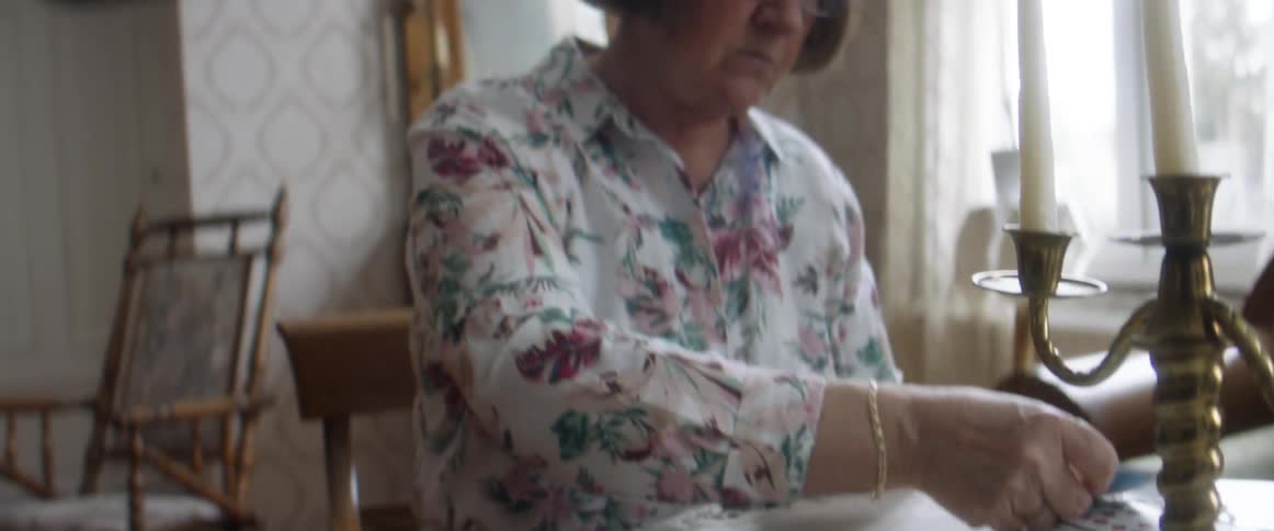 A woman in a room with glasses playing cards with a wall and window in the background