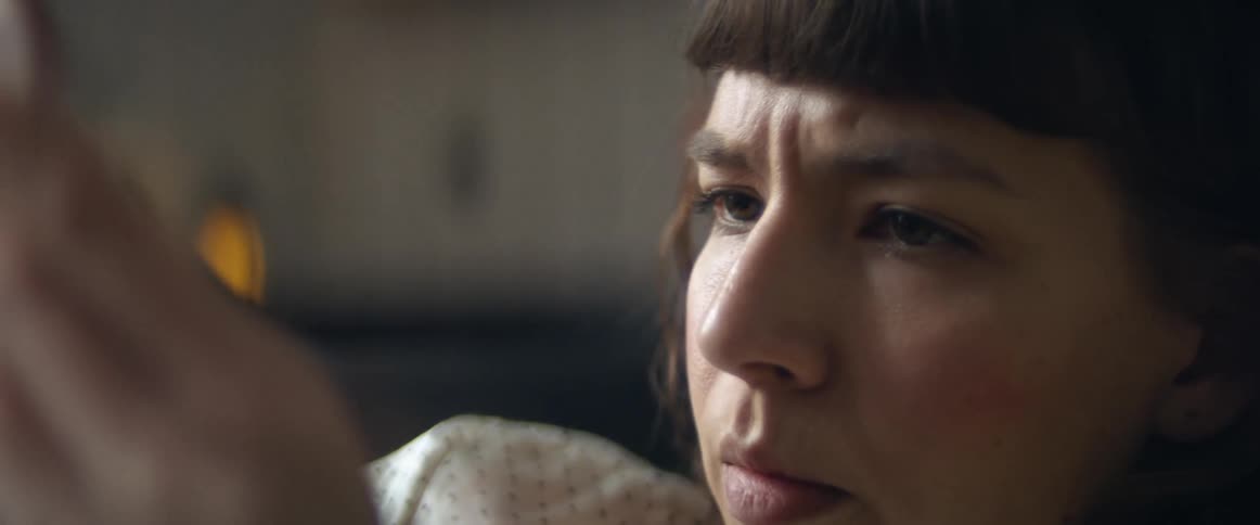 A woman with short blunt bangs scrolls through her smartphone