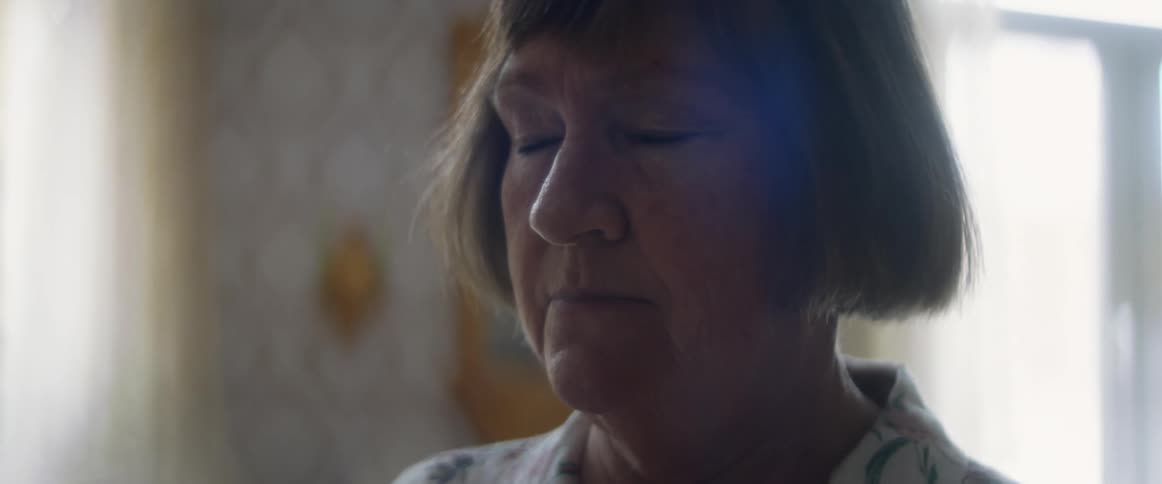 A white female standing in a room closing her eyes