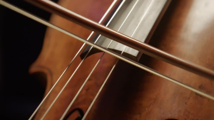 A person uses a bow to play the cello