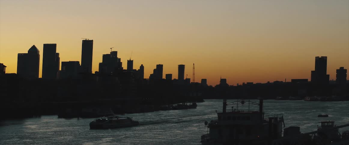 A river with boats with the city skyline the sky and clouds in the background