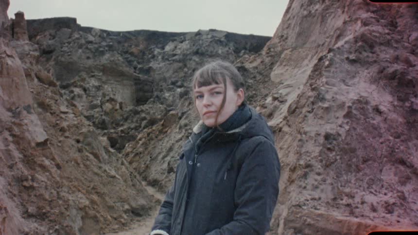 A portrait of a woman standing outside near rocks