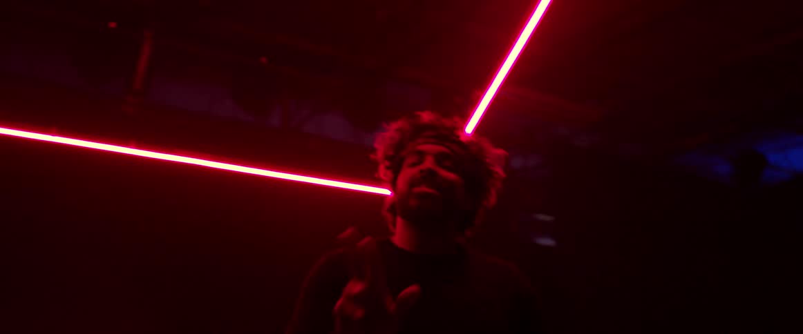 Man wearing a head band dancing on a dark room under red neon lights