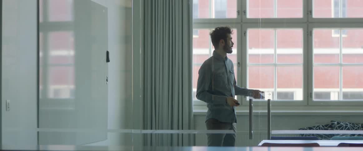 A man gives a presentation in a conference room with glass doors
