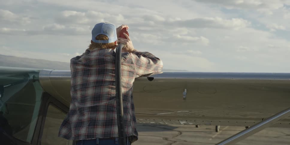 A man in a flannel shirt looks out across a field