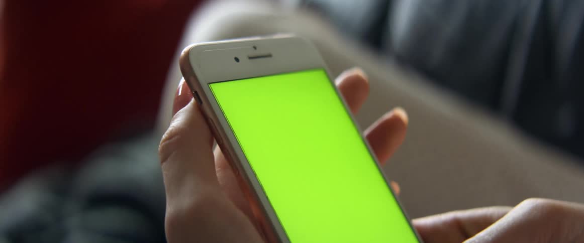 A woman resting on a couch scrolling on the screen of an iphone