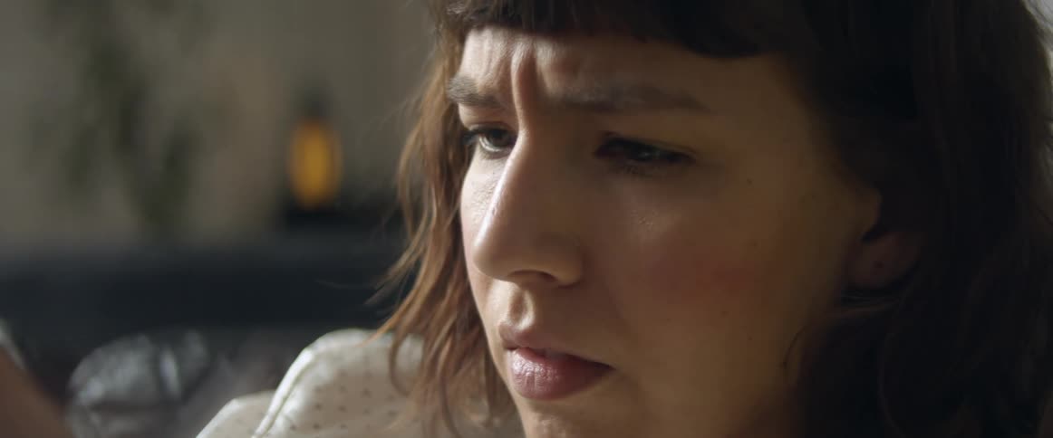 A woman looks down at her smart phone with a look of concern on her face