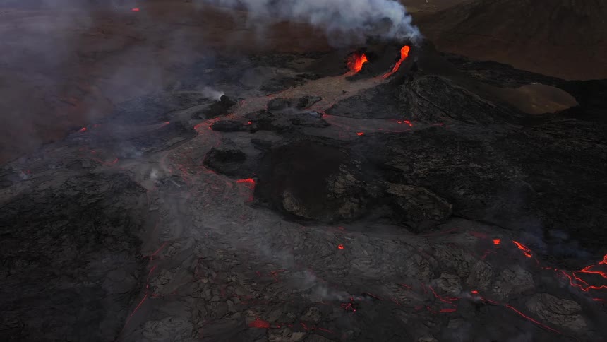 Smoke rises as erupting volcano spews molten hot lava and oozes a river of hot lava
