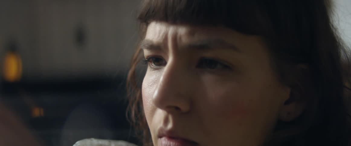 Woman scrolls through mobile phone frowning