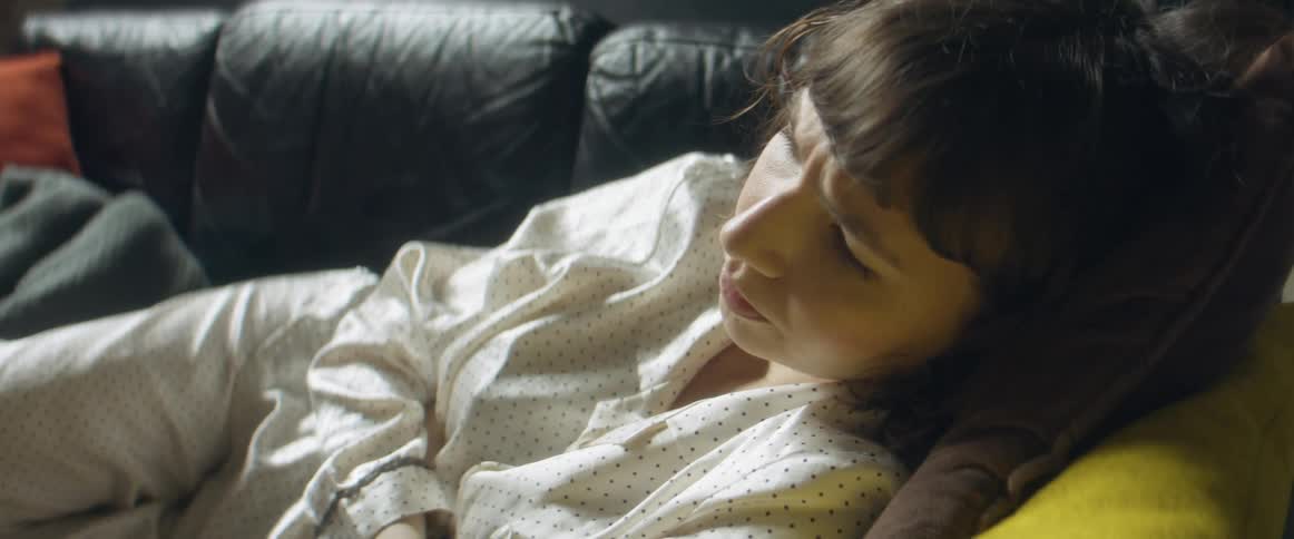 A sick woman lying down on a couch in a living room