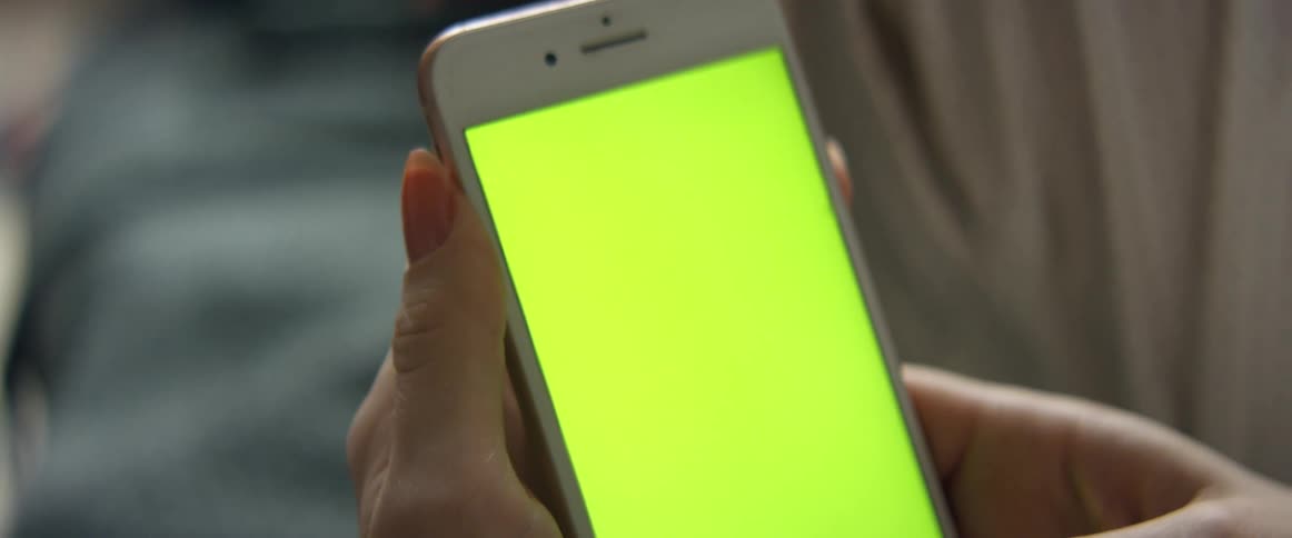 A woman scrolls through her smartphone while sitting with her legs up
