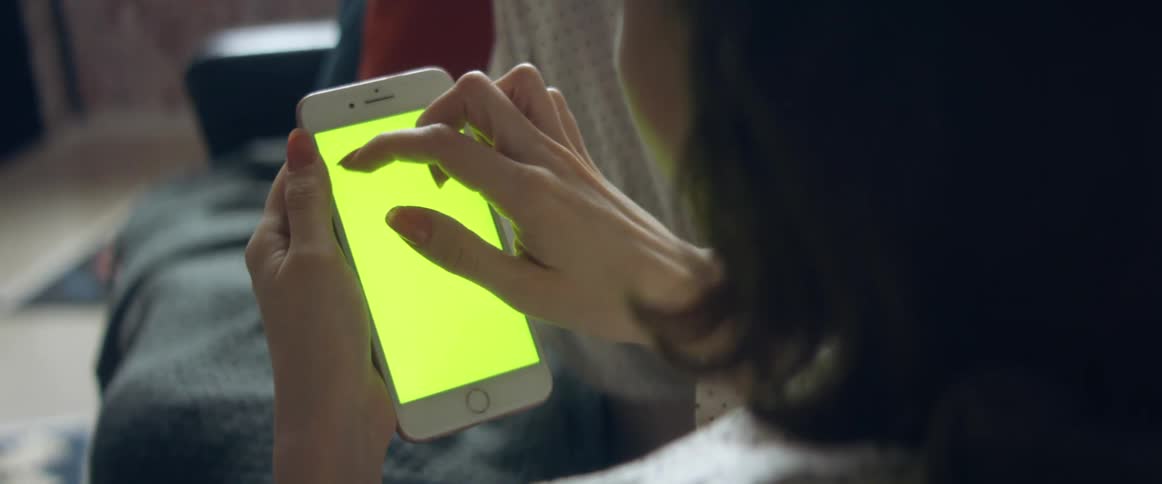 A teenage girl touches the screen of her cell phone that is solid yellow