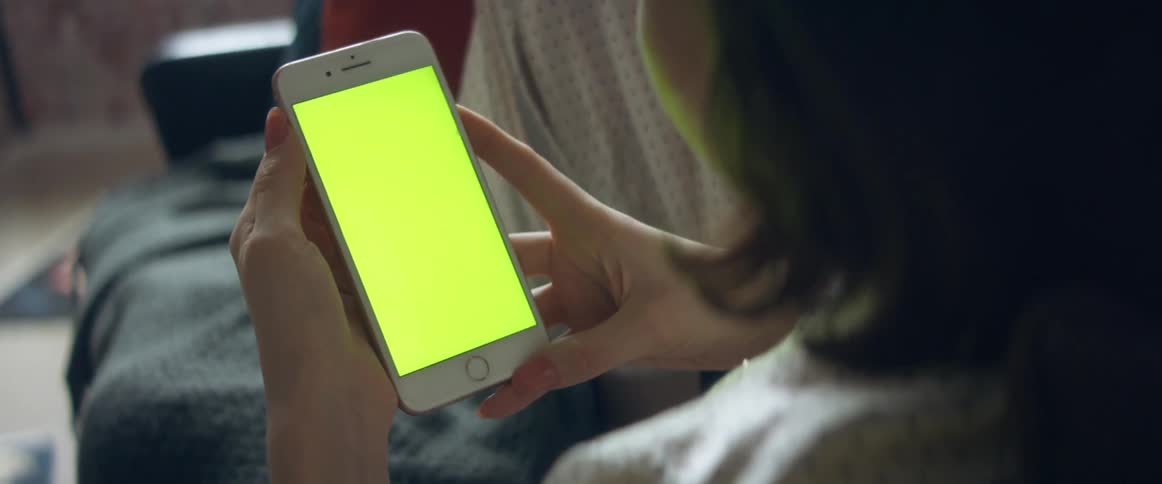 A woman is sitting down looking at her cell phone