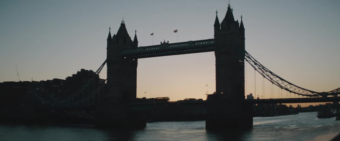 A bridge over a river with buildings the sky and clouds in the background