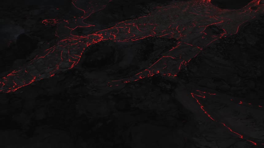 As a volcano erupts glowing hot lava spews out of it and flows down its side