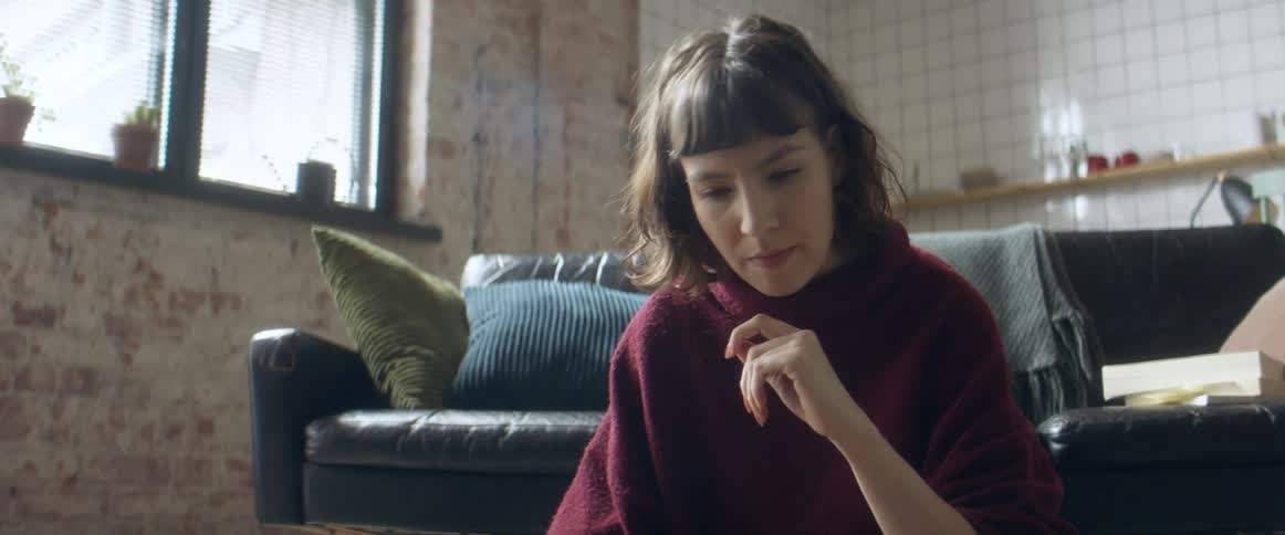 Woman sitting over a rug in the living room working on a laptop