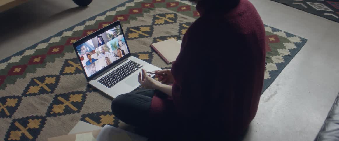 A woman in a room sitting on the floor in front of a laptop with a wall and door in the background