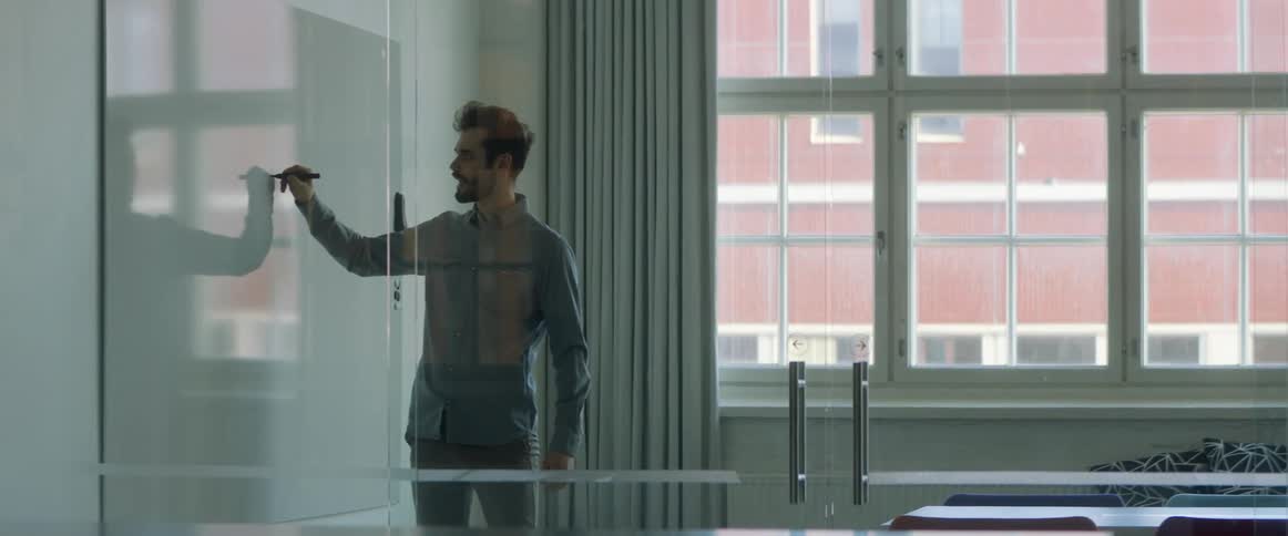 A man writing on a white board at an office