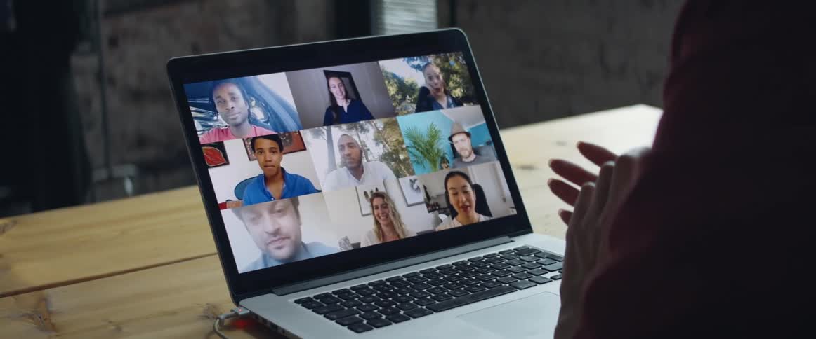 A person participates in a video conference using a table while sitting at a wooden table indoors during the day