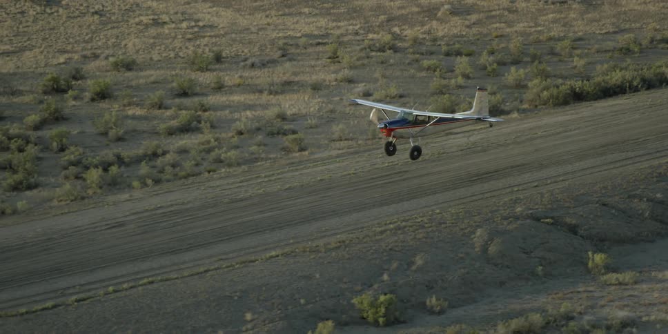 Small single prop plane lying just above the dirt runway