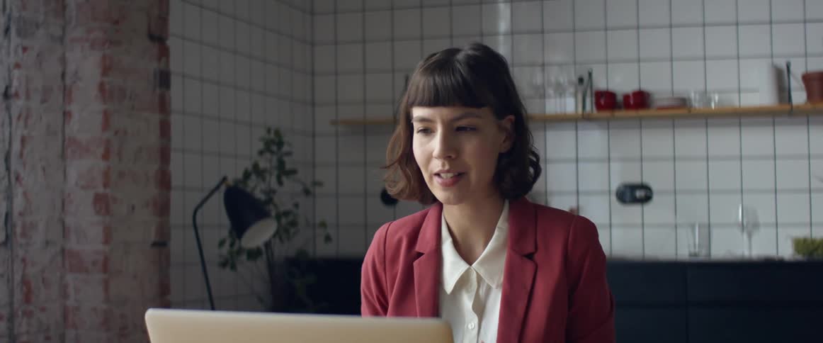 A woman sits in front of a laptop having a video call