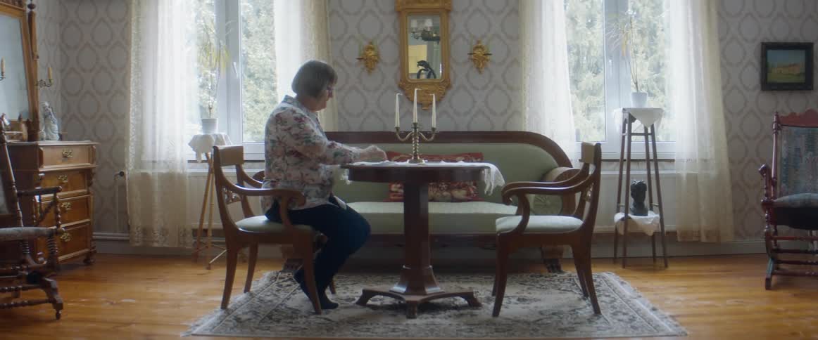 Woman sitting at a table playing solitaire in the living room at home