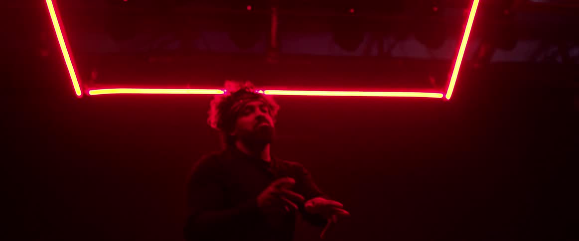 Man wearing a head band dancing on a dark room under red neon lights