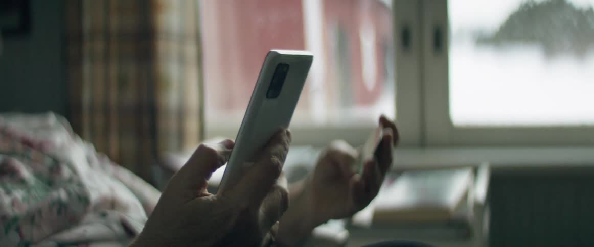 A woman in a room using a smart phone with a wall and window in the background