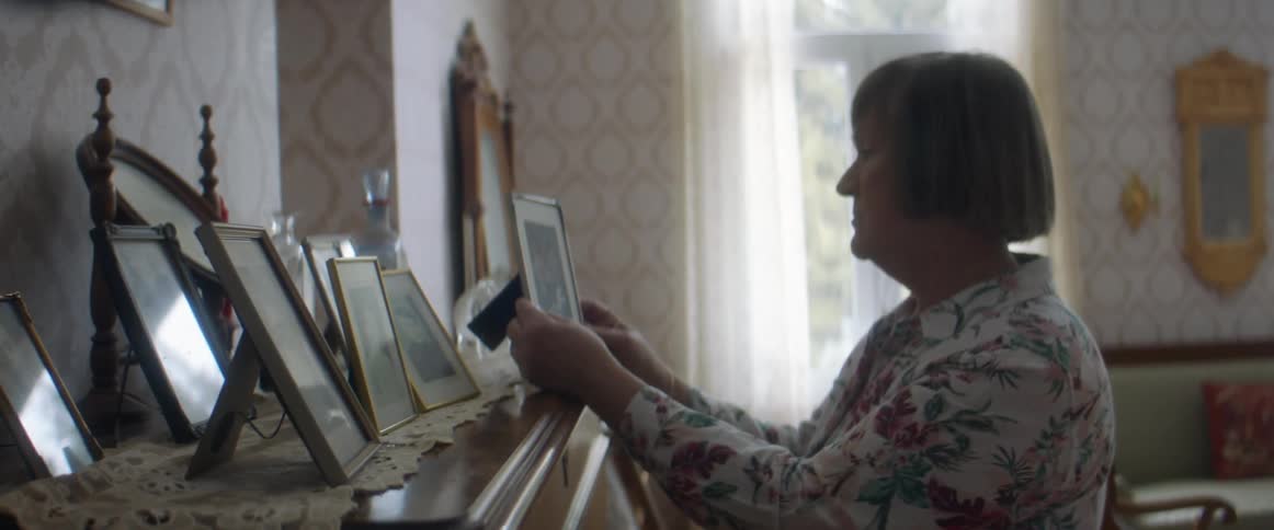 Woman standingin the living room at home looking at framed pictures