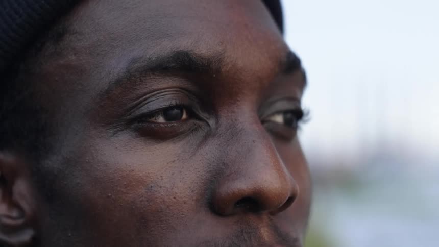 A young man staring off lost in thought outdoors