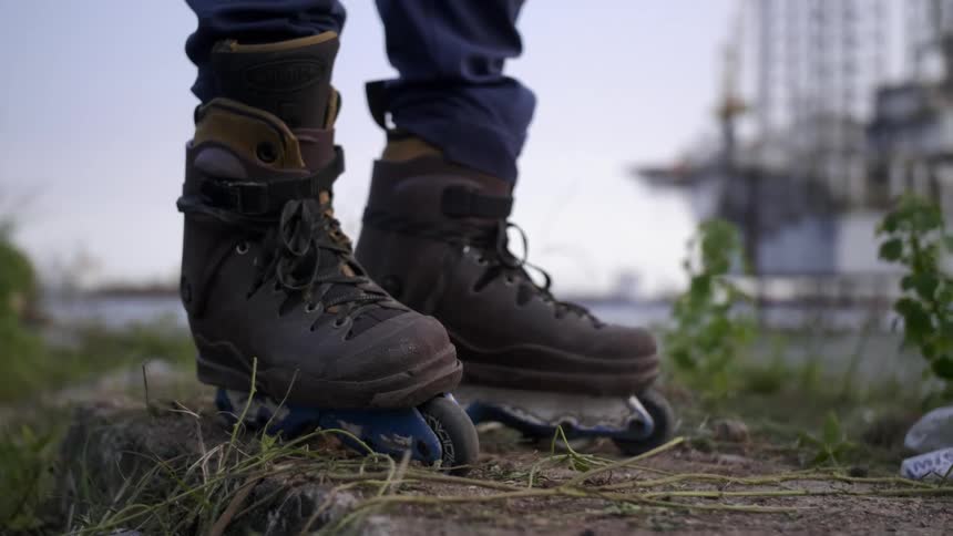 Close up of roller skates on a persons feet as they stand next to the water