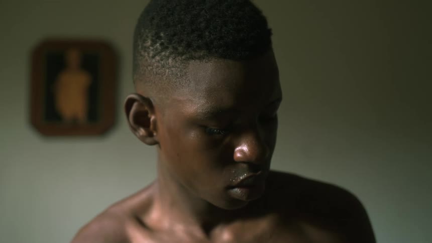 A boy in a room with a wall in the background