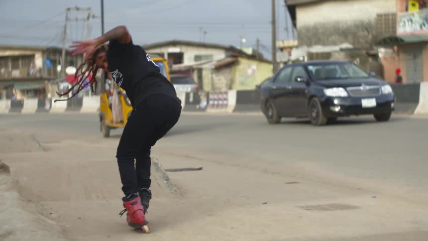 Man on skates performs jump trick using ramp next to busy street across from apartments