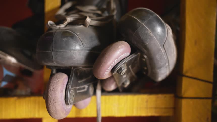 A pair of in line skates sits in a cubby hole on a shelf at a skating rink